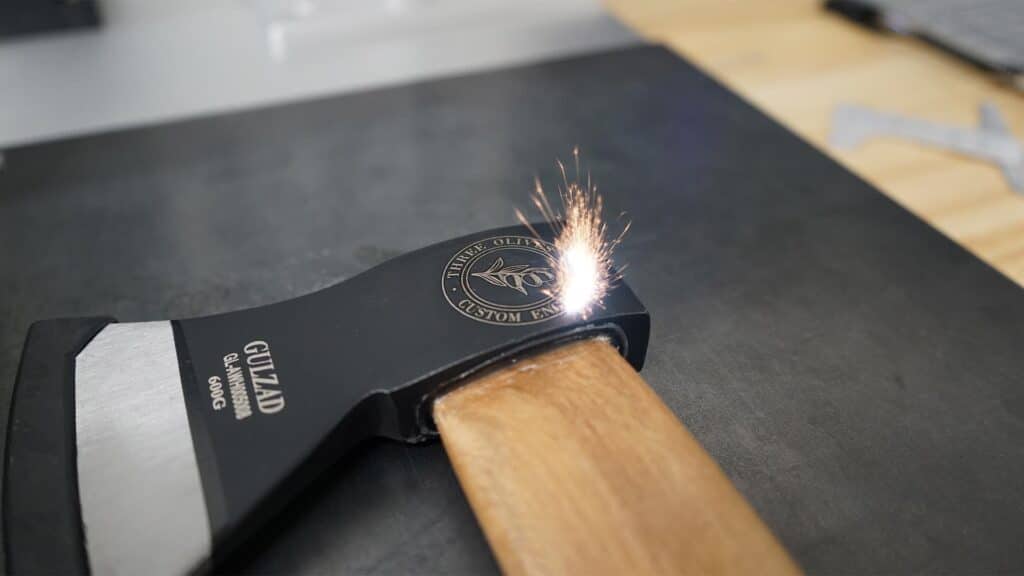 Custom wood engraving process on a black laser engraver with sparks flying.
