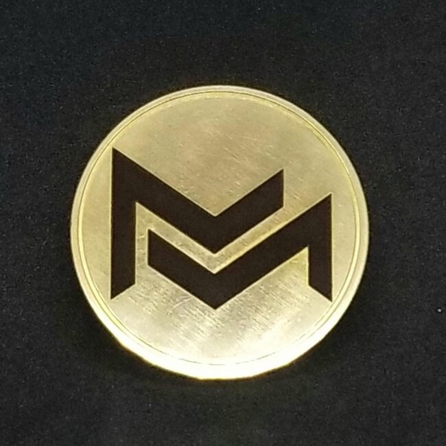 Shiny gold coin with engraved Monero cryptocurrency logo on black background.