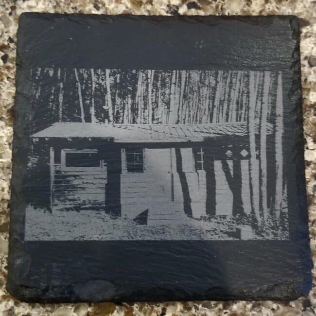 Rustic wood cabin engraved on black slate stone, custom wood carving art, outdoor decor, Three Olives Engraving.