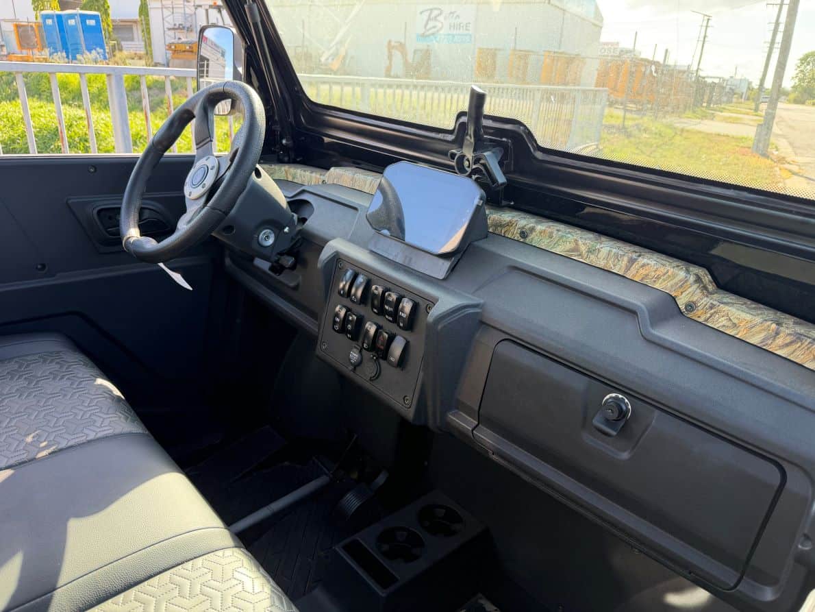 Utility vehicle dashboard with electronic controls and steering wheel.