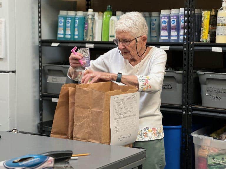 volunteer packing food at Tri-Lakes Cares no-cost grocery market Monument CO