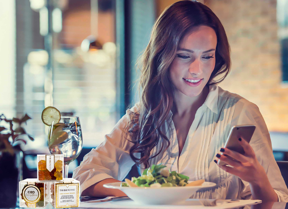 woman enjoying delta 8 gummies after her meal, while relaxing on her phone