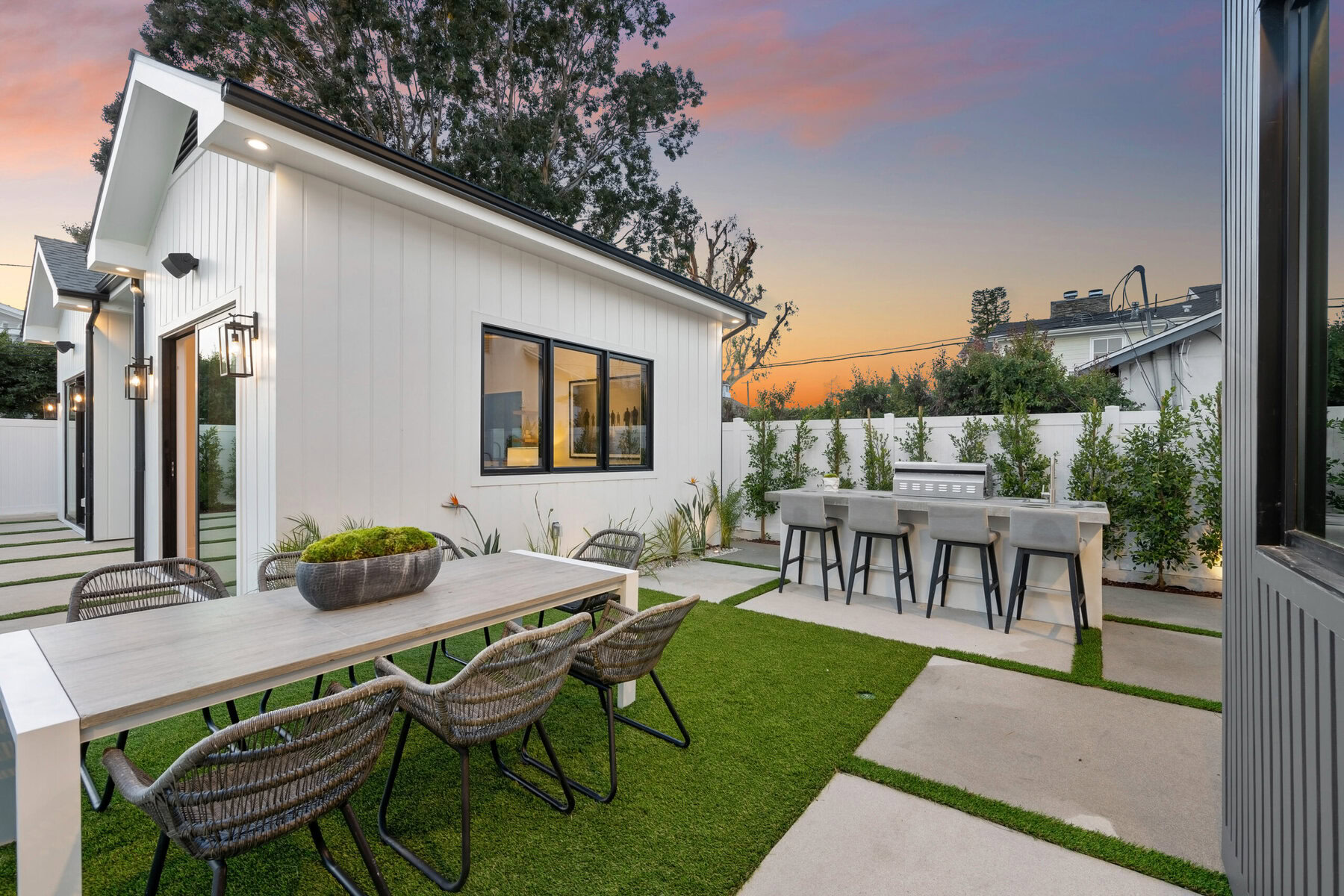 Modern backyard with outdoor dining and kitchen area at sunset