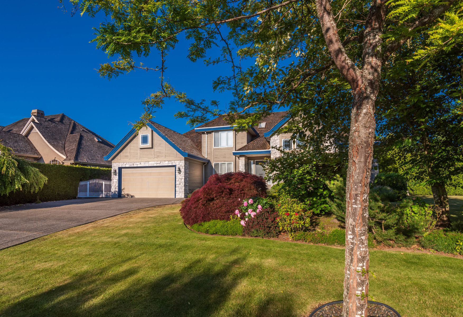 Suburban house with beige siding, stone accents, and a well-maintained garden.