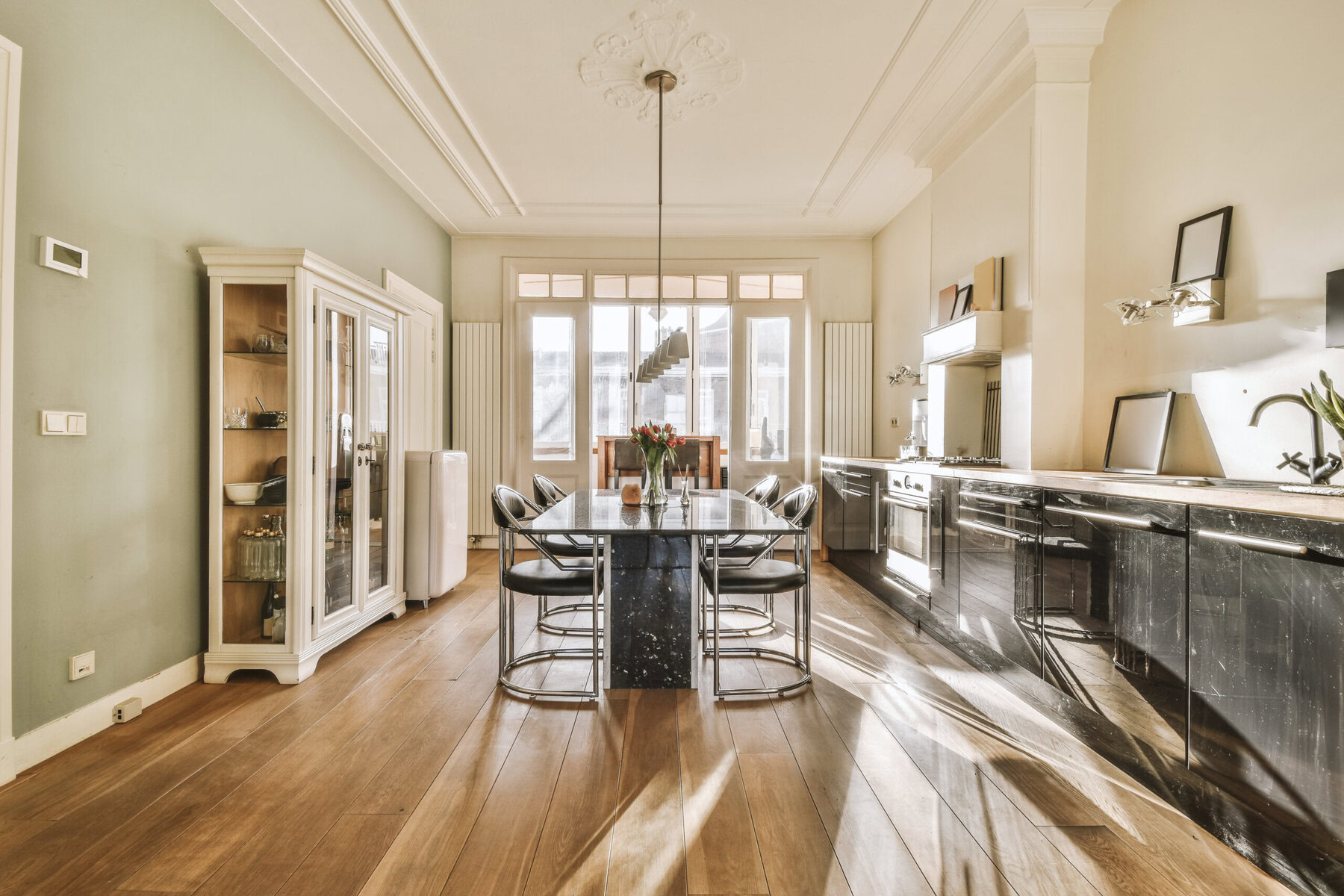 Modern dining room and kitchen with natural light and dark accents
