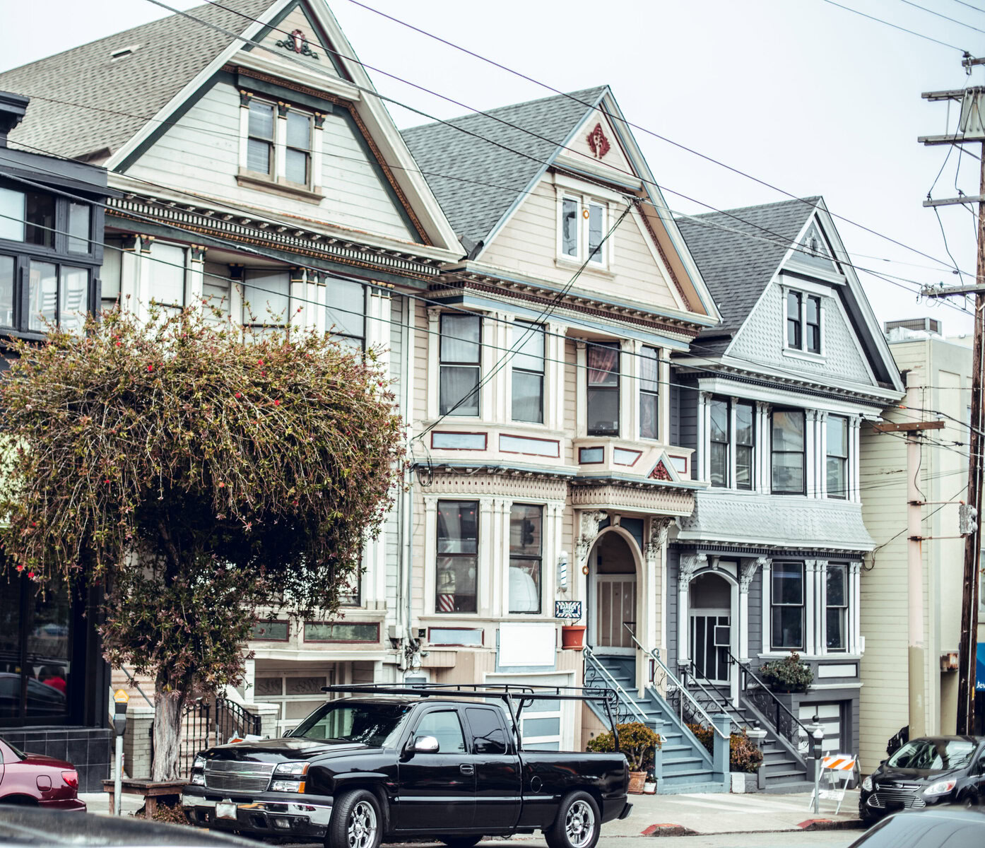 Row of Victorian-style houses with a black pickup truck parked in front.