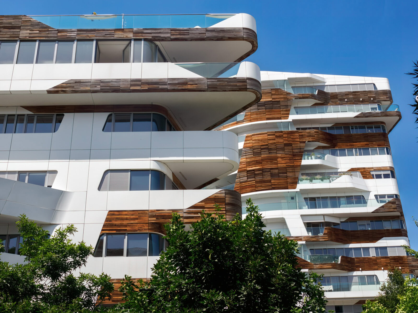 Modern building with white and wood facade against a clear blue sky.