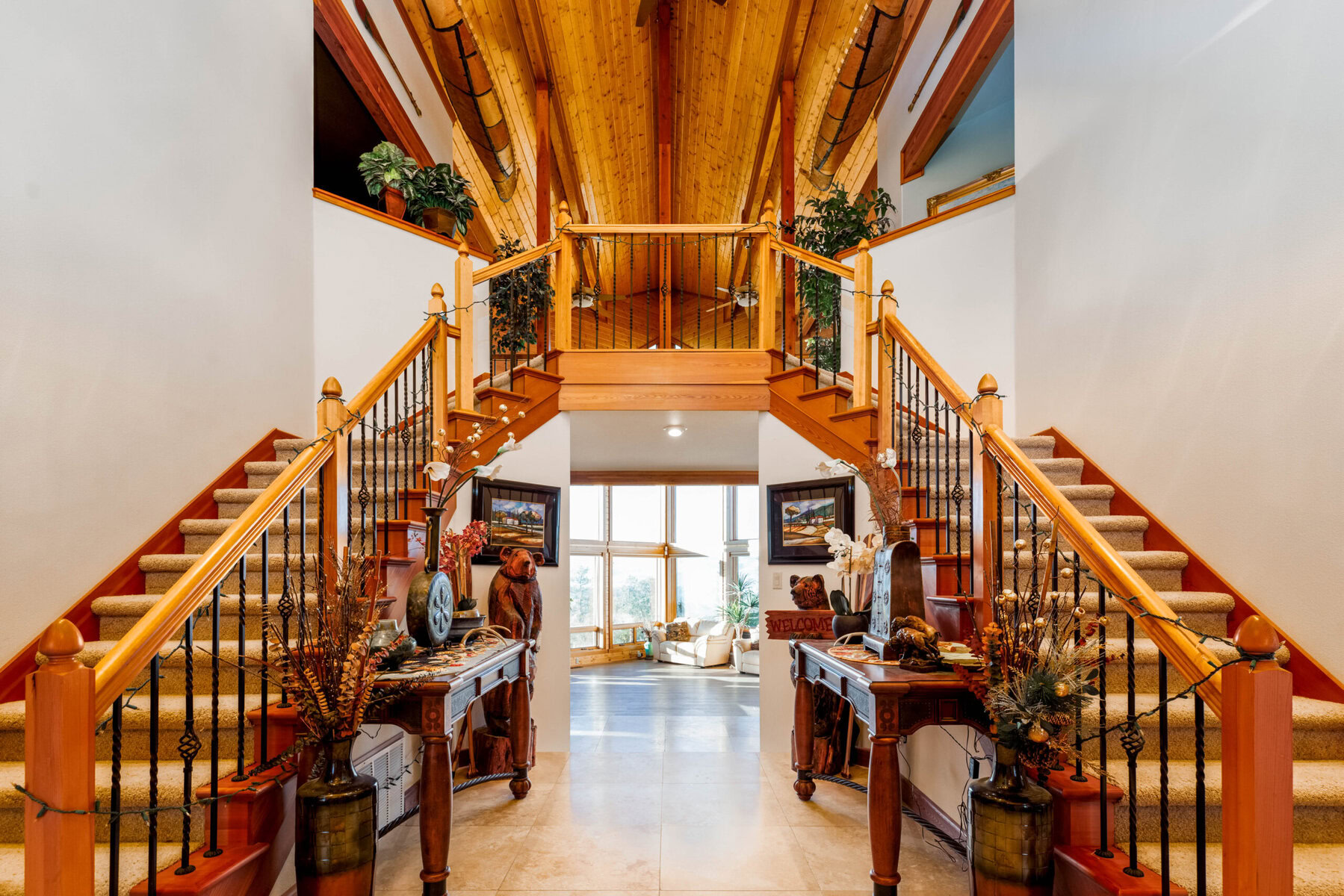 Grand wooden staircase in a spacious, well-lit home entrance.