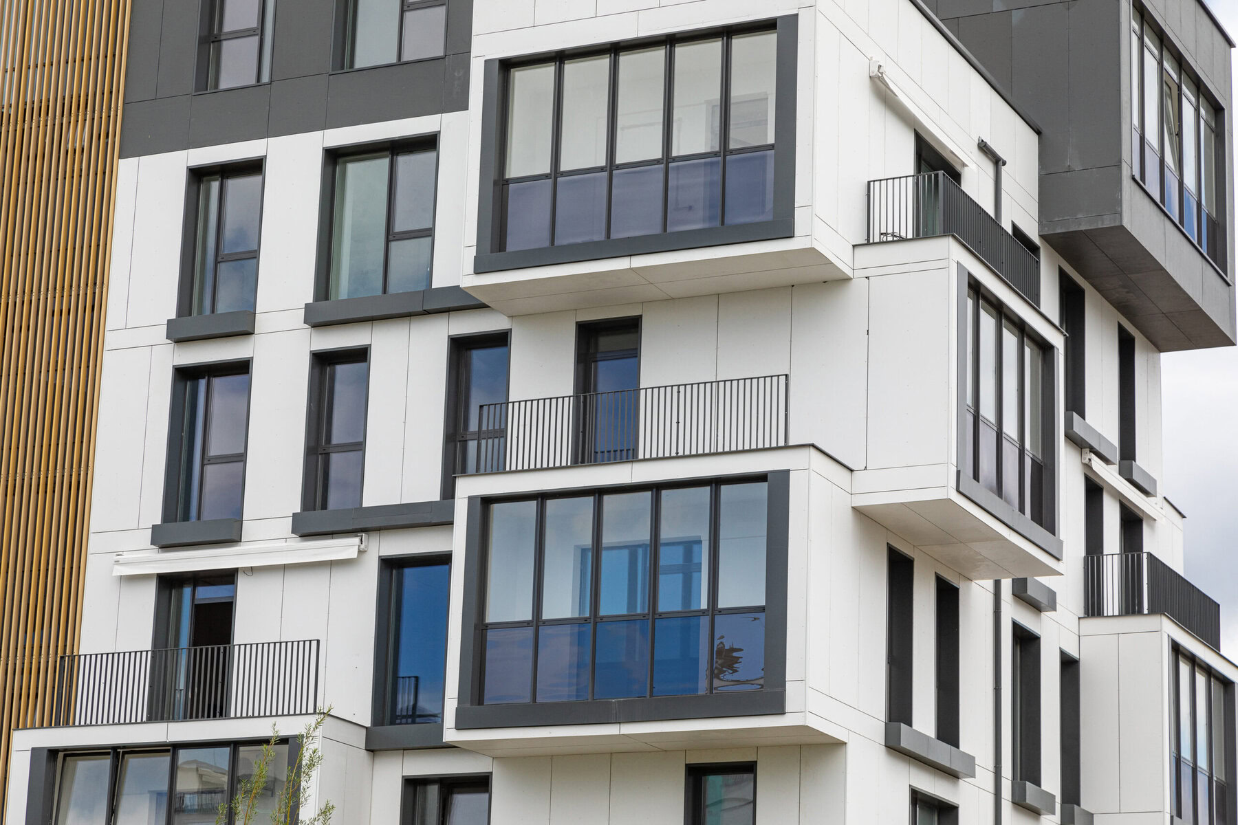 Modern white and gray apartment building with balconies and large windows