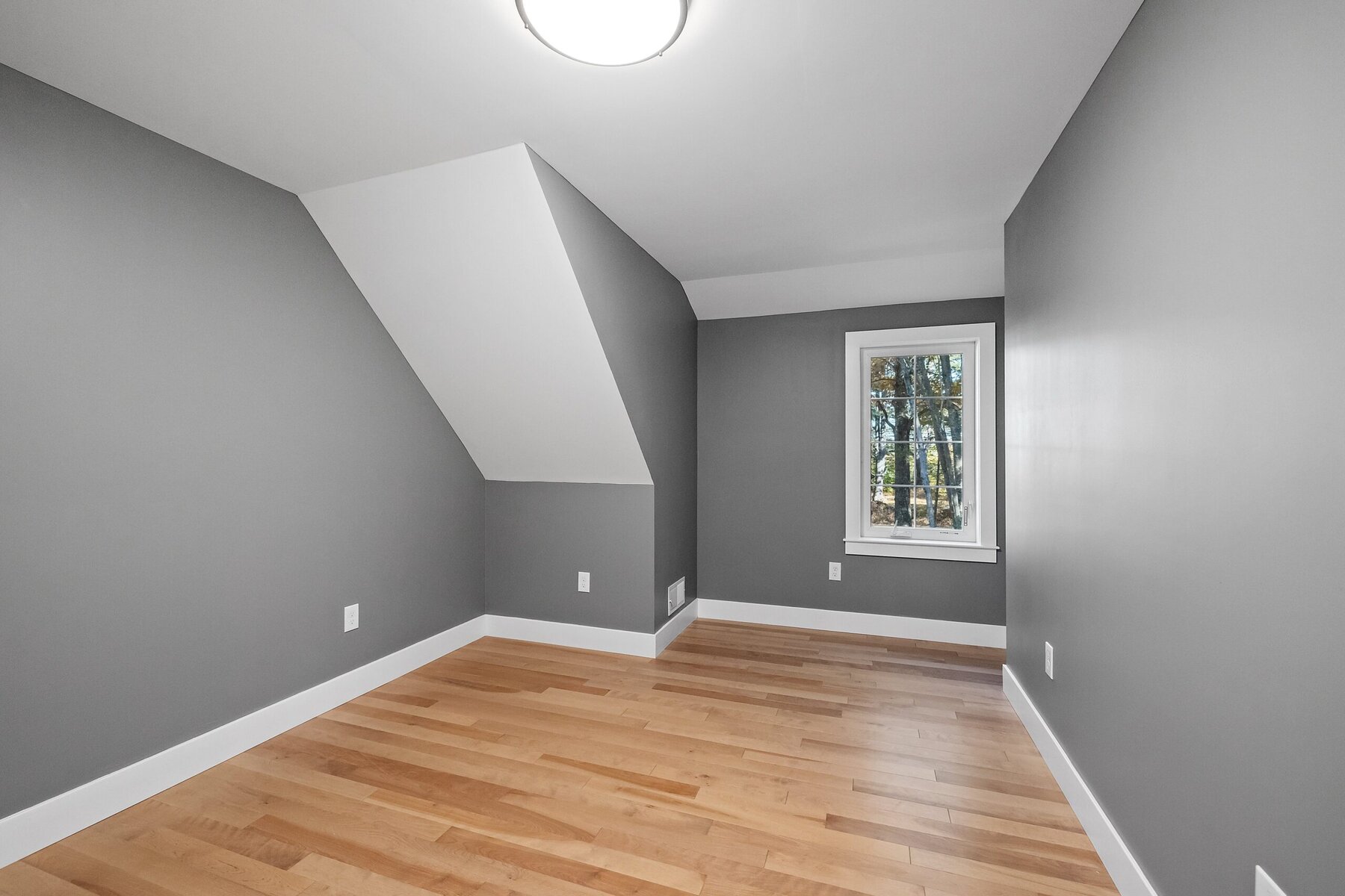 Empty room with gray walls, hardwood floor, and a window
