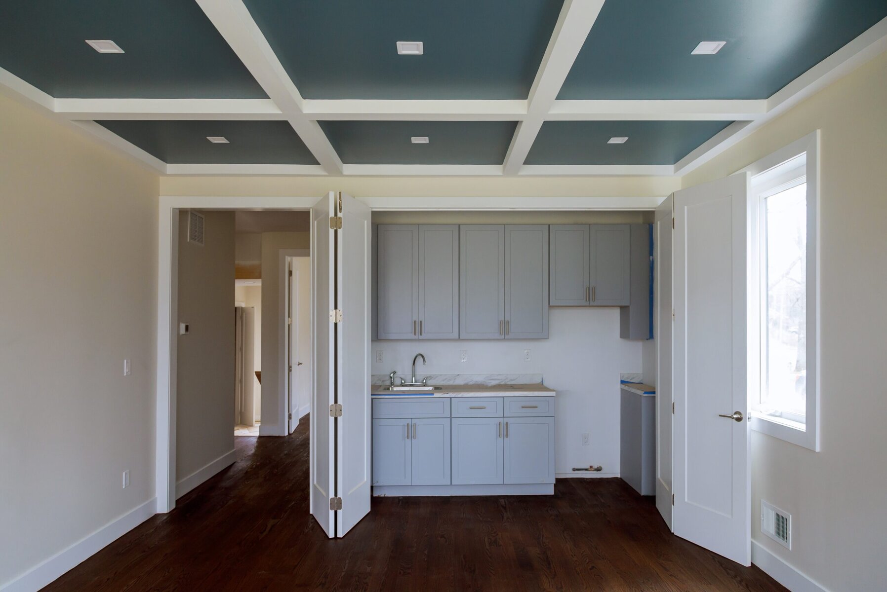 Empty room with blue coffered ceiling and light gray cabinets