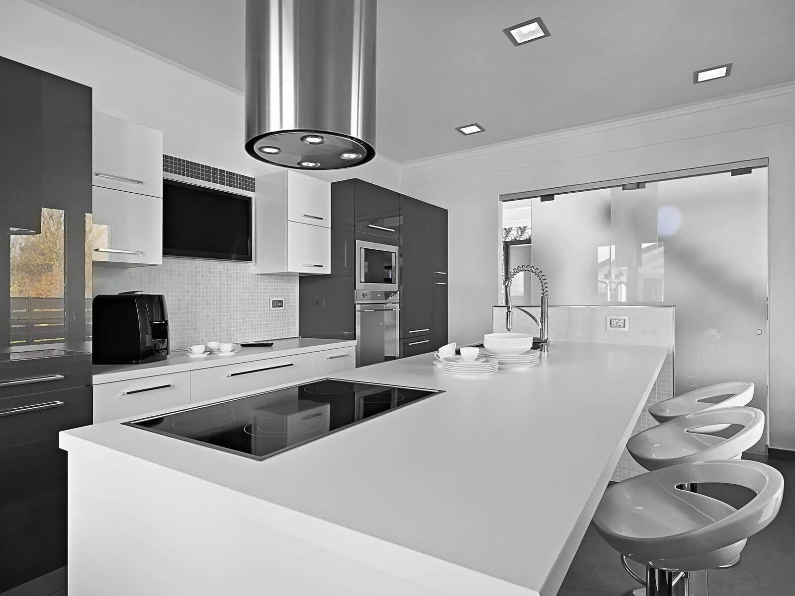 Modern kitchen with white countertops, dark gray cabinets, and stainless steel appliances