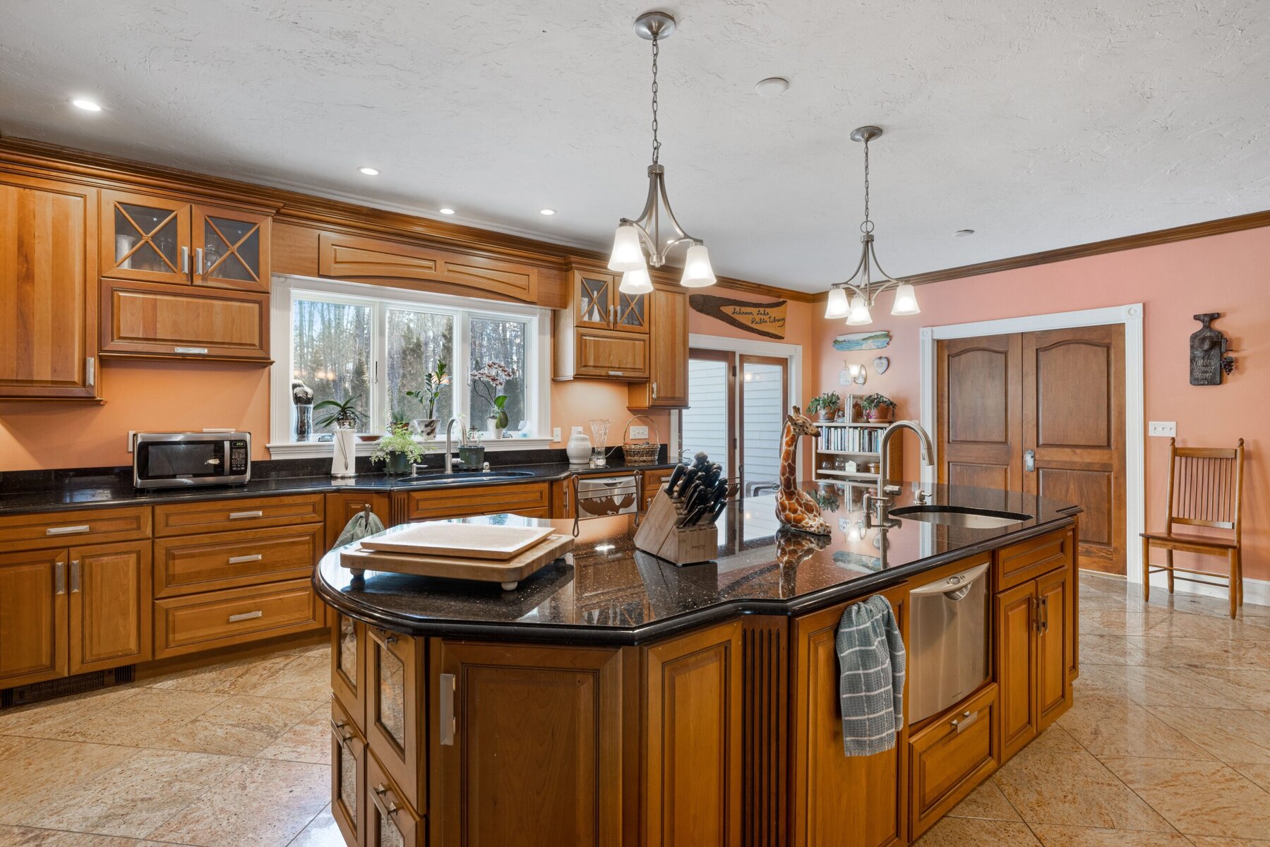 A spacious kitchen with wooden cabinets, a large island, and a window.