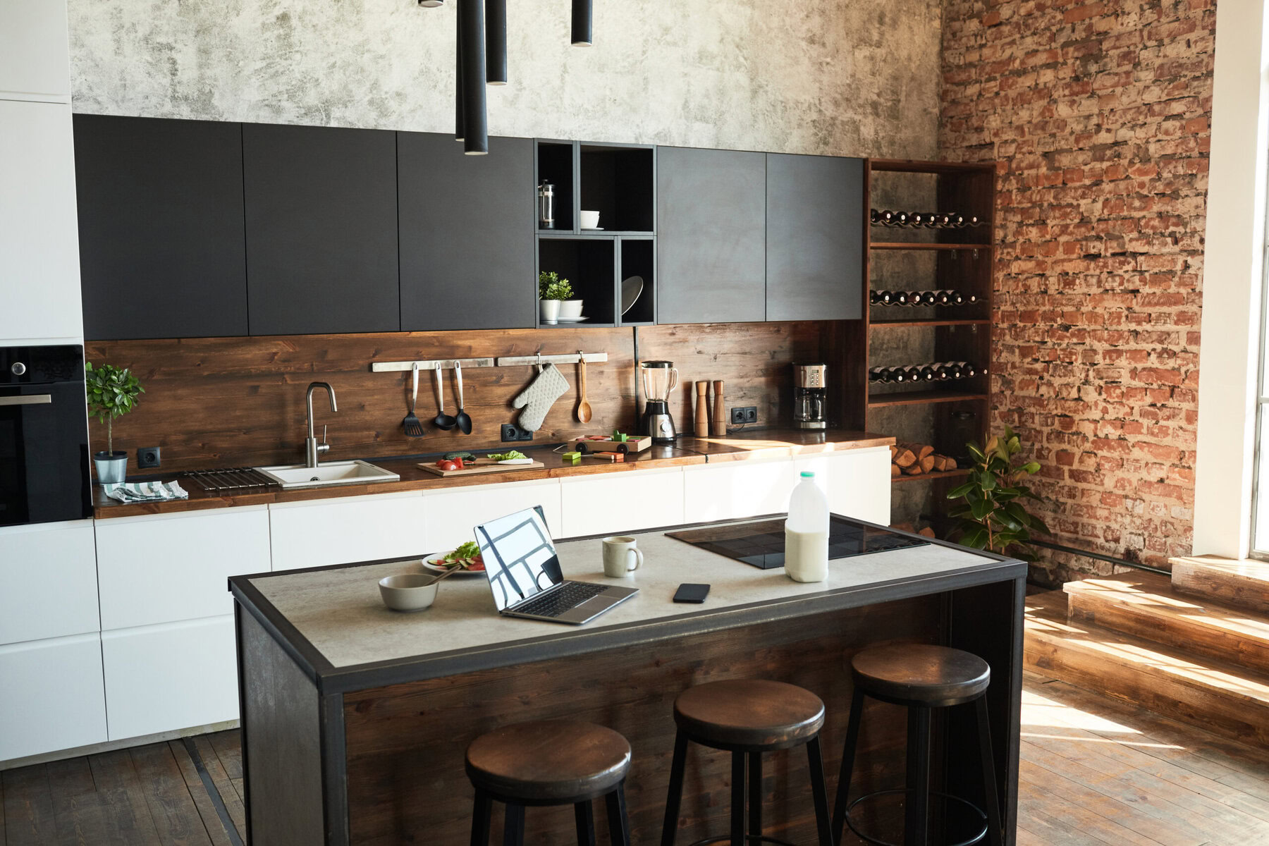 Modern kitchen with dark cabinets, wood accents, and a laptop on the island.