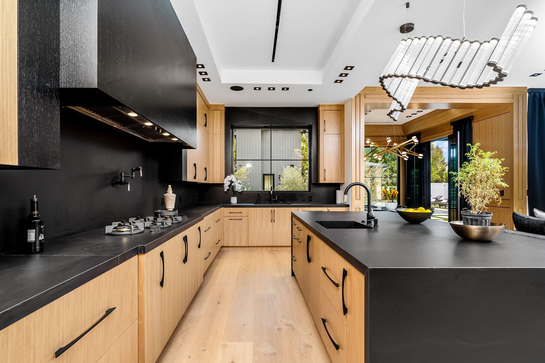Modern kitchen with black countertops, light wood cabinets, and large island.