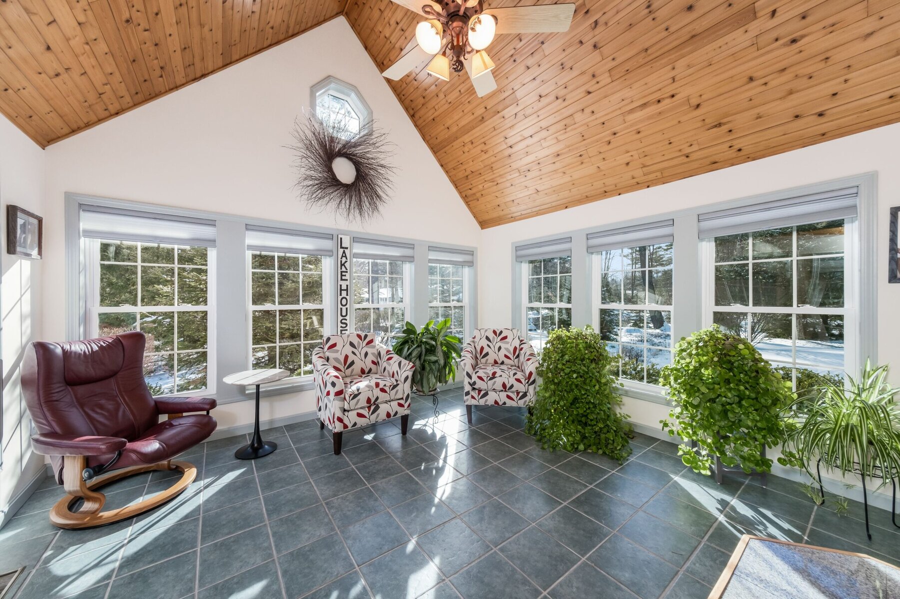 Sunroom with vaulted wood ceiling, large windows, and various seating