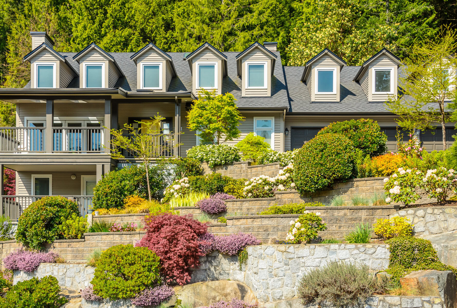 Large house with multiple dormers and a terraced garden