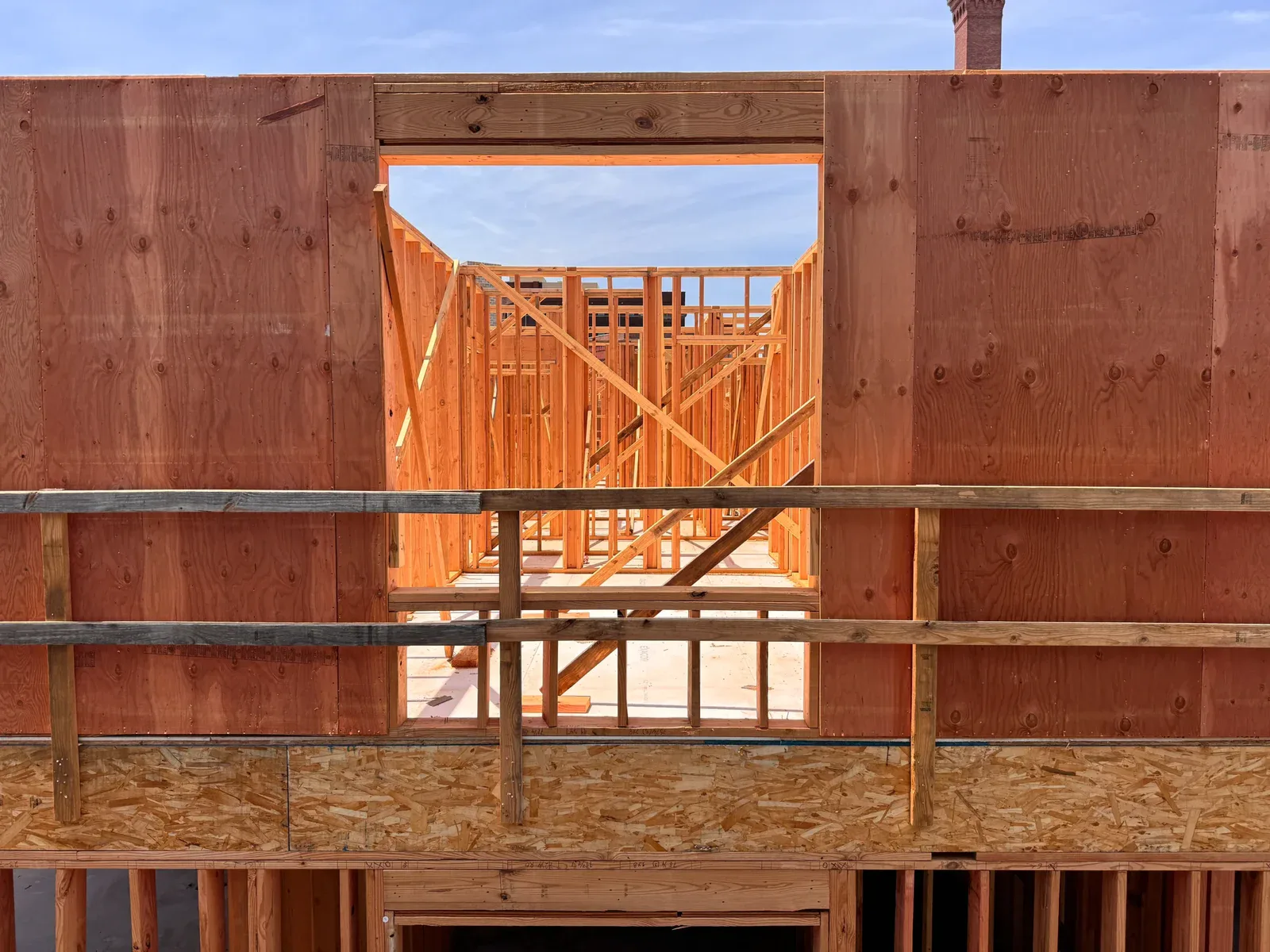 Unfinished wooden house frame with a blue sky visible through a window opening.