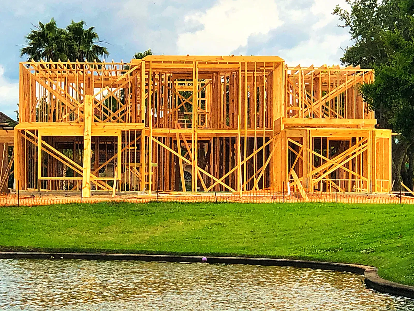Wooden framework of a house under construction by a body of water