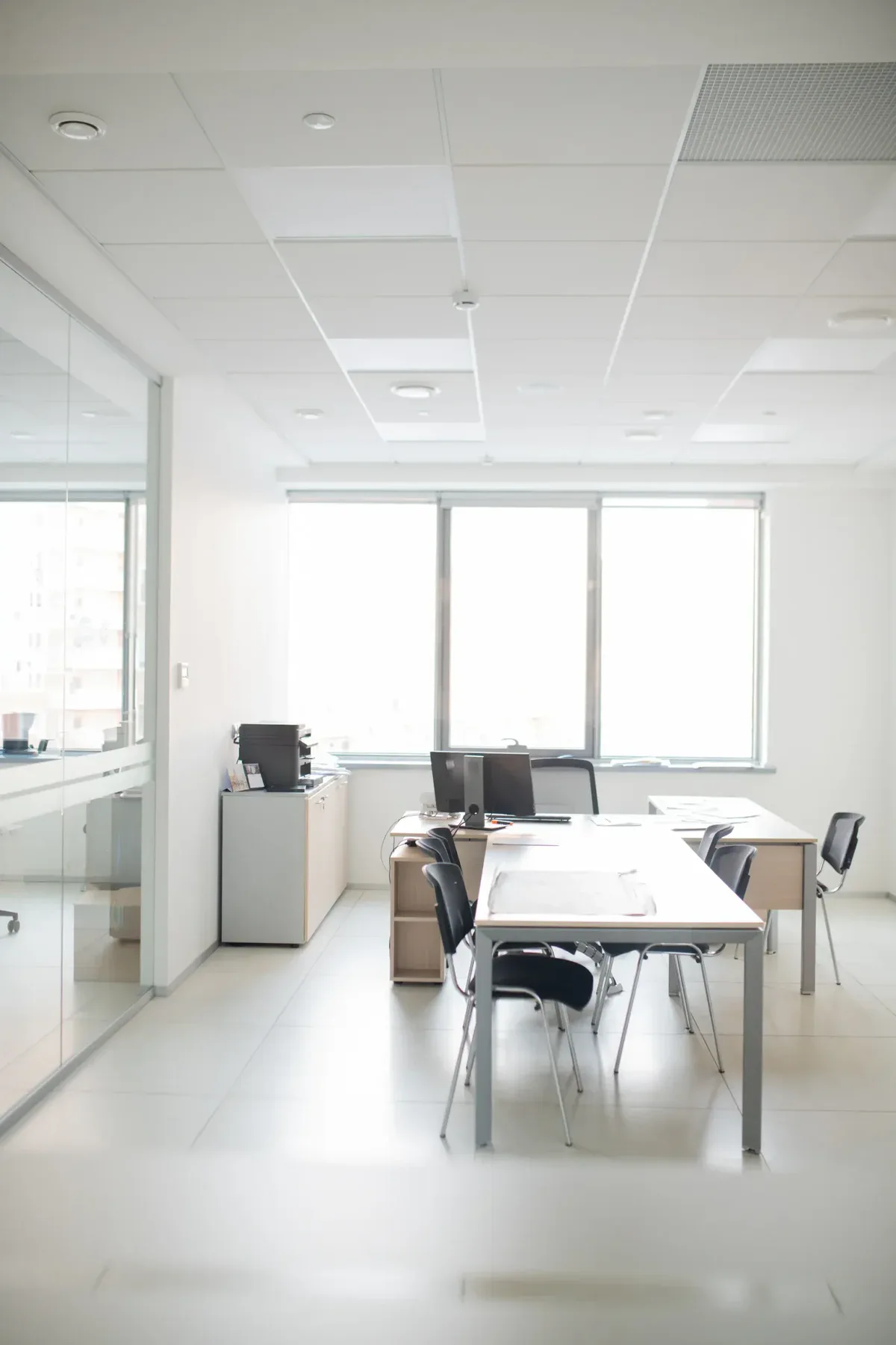Bright, empty office space with desks, chairs, and large windows