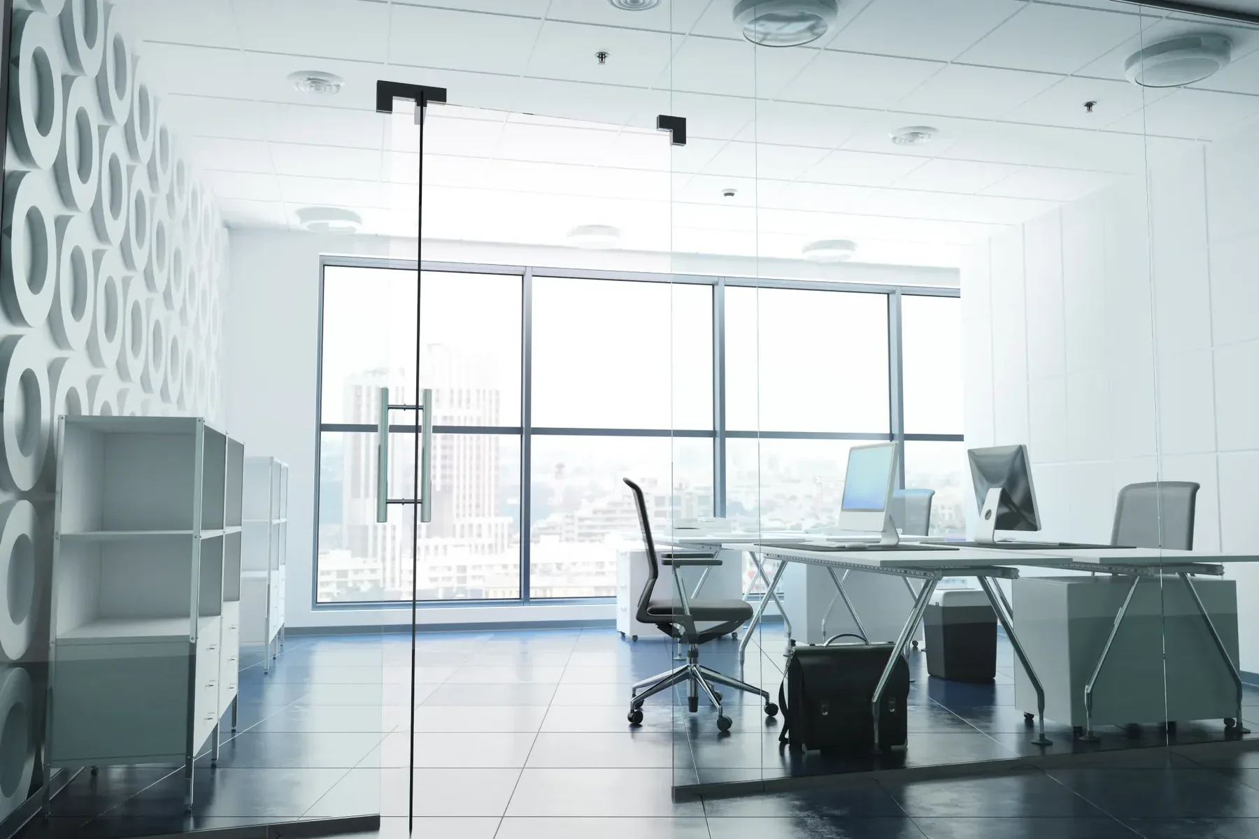 Modern office interior with glass door, desks, chairs, and large windows