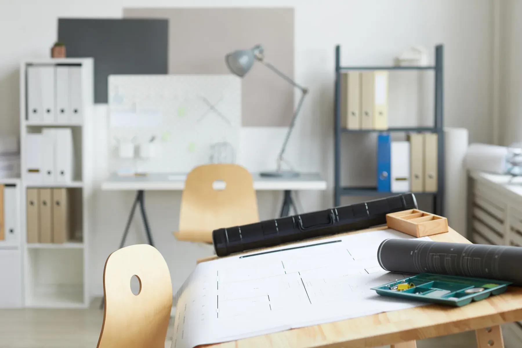 Architect's desk with blueprints, tools, and office supplies in a bright room