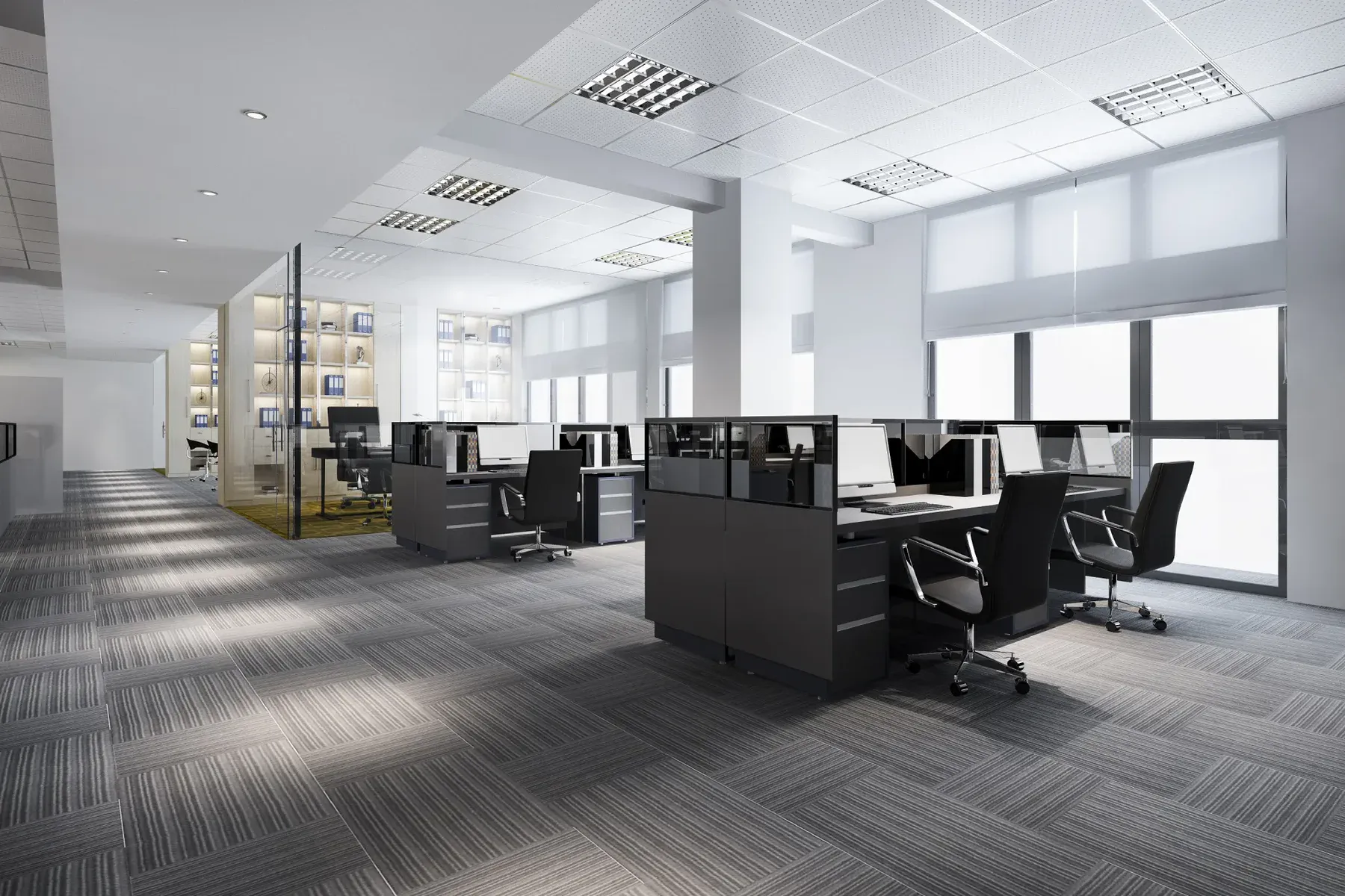 Modern open-plan office with grey cubicles, chairs, and computers