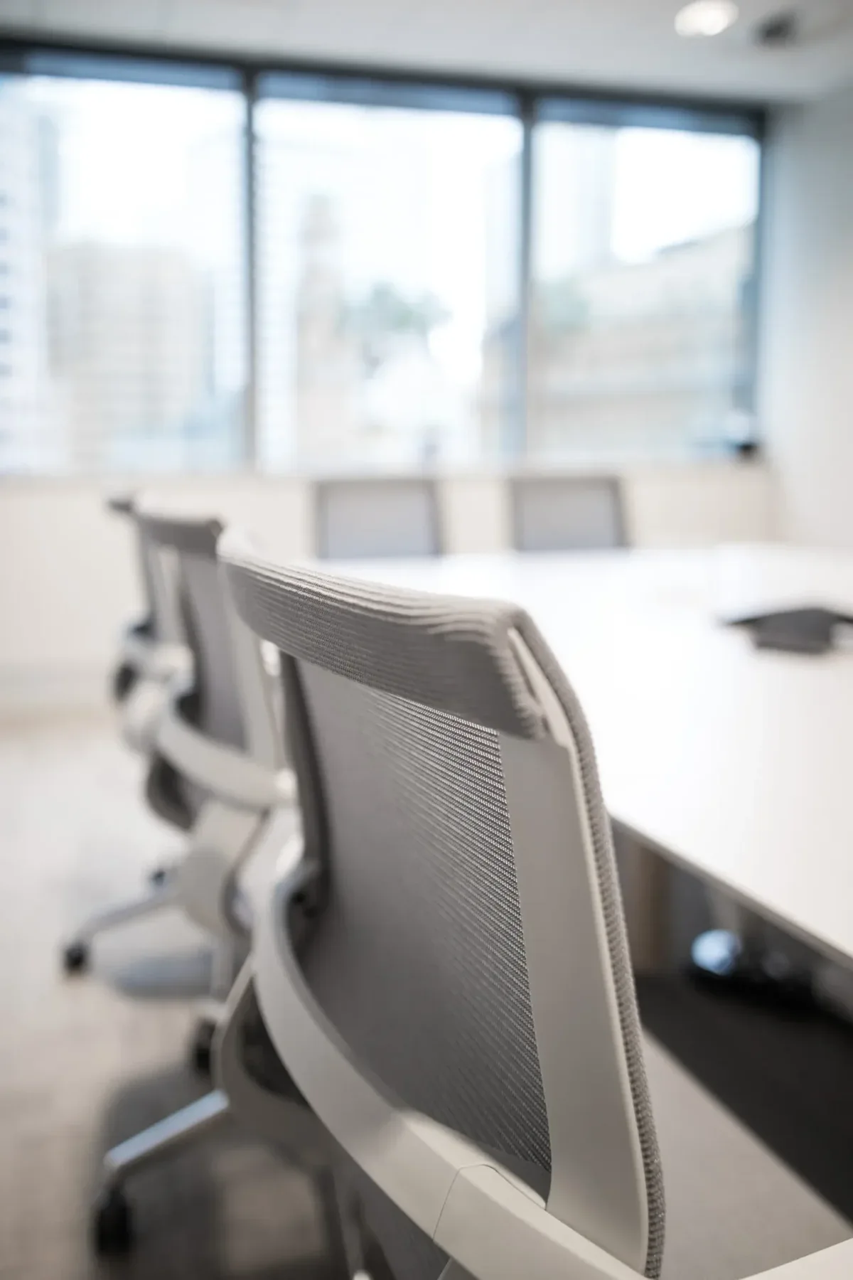 Empty modern conference room with gray chairs and a large window.