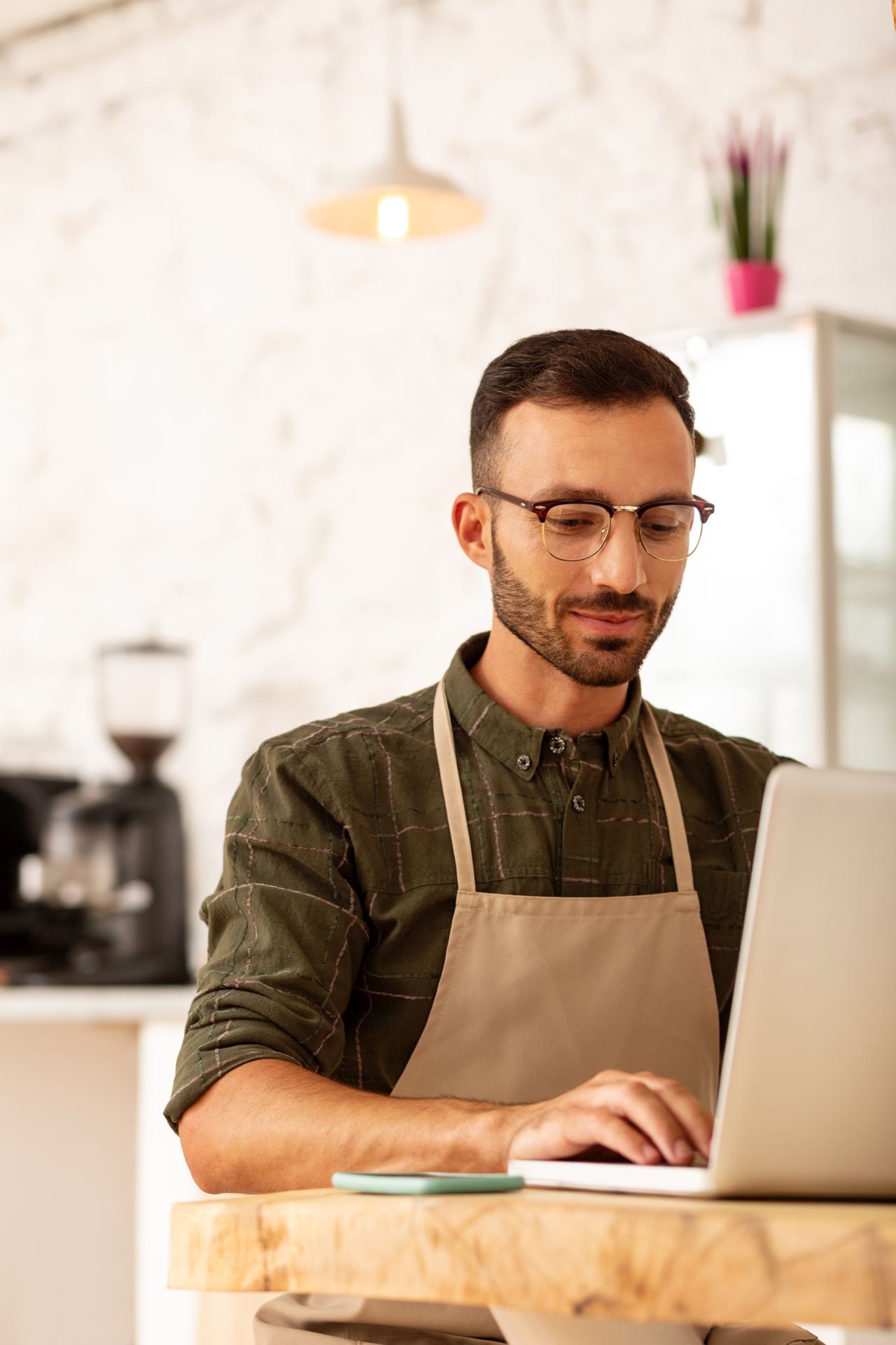 Owner of coffee shop sitting near laptop while developing business strategy