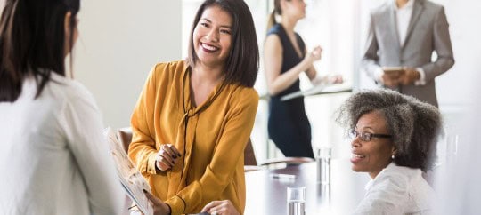 Business professional woman handing some documents to another woman