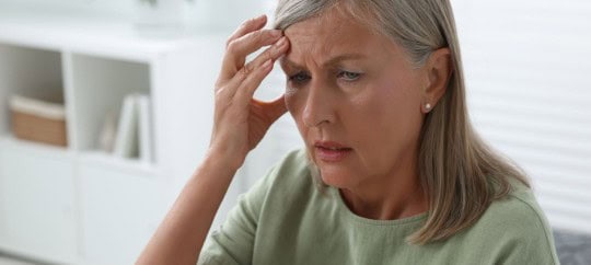 elderly woman looking frustrated at a piece of paper