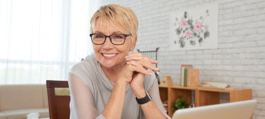 Elderly lady smiling over her laptop in her office