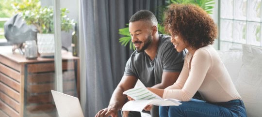 Man and woman smiling while looking at computer and working on finances