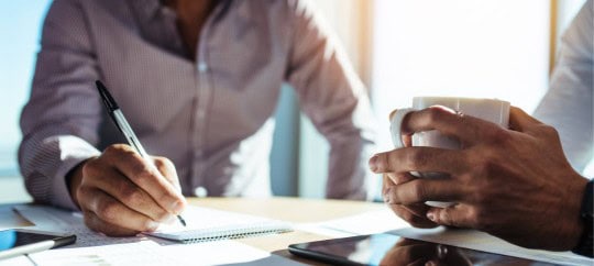 Two business professionals at a table with paperwork