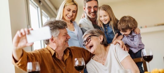 generations of a family smiling while taking a group photo