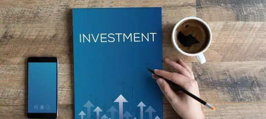investment book on a table next to a cup of coffee