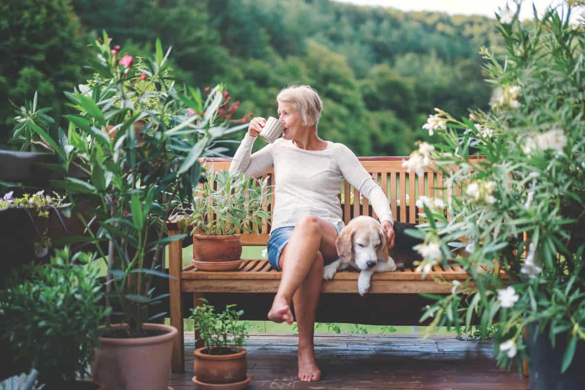 Woman Sitting on a bench drinking coffee with a dog