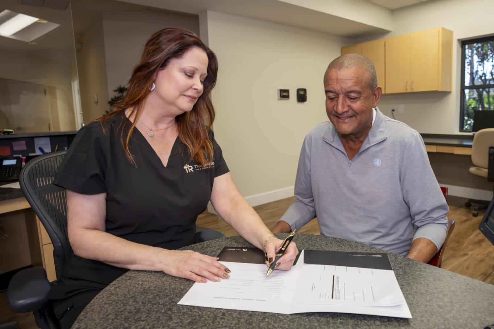 A dental assistant helps a patient fill out paperwork