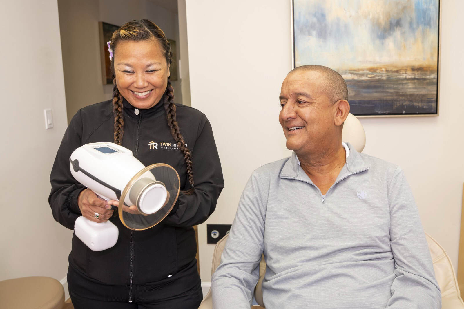 A dental assistant shows a patient a digital X-ray tool