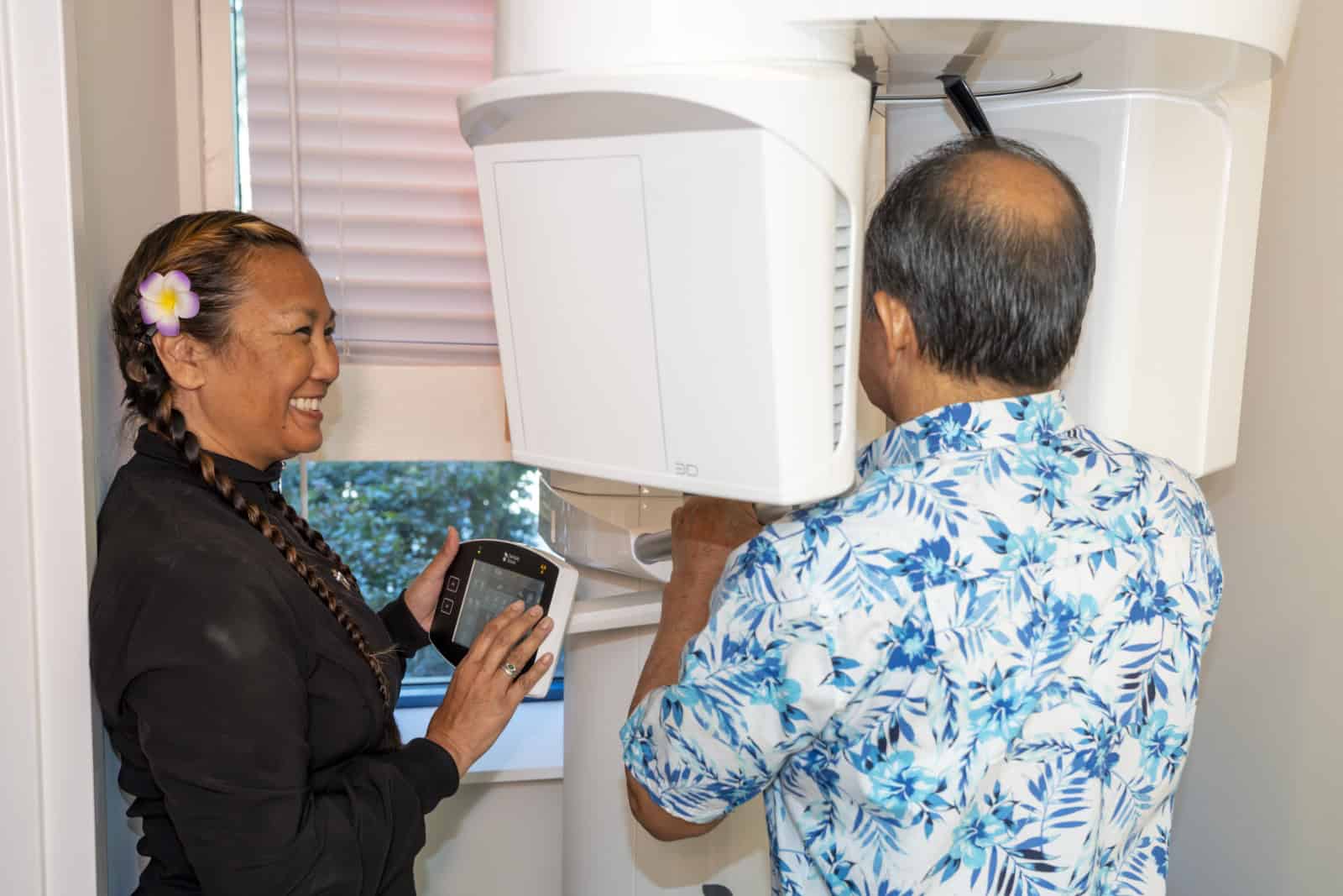 A dental assistant helps a patient use a CT scanner