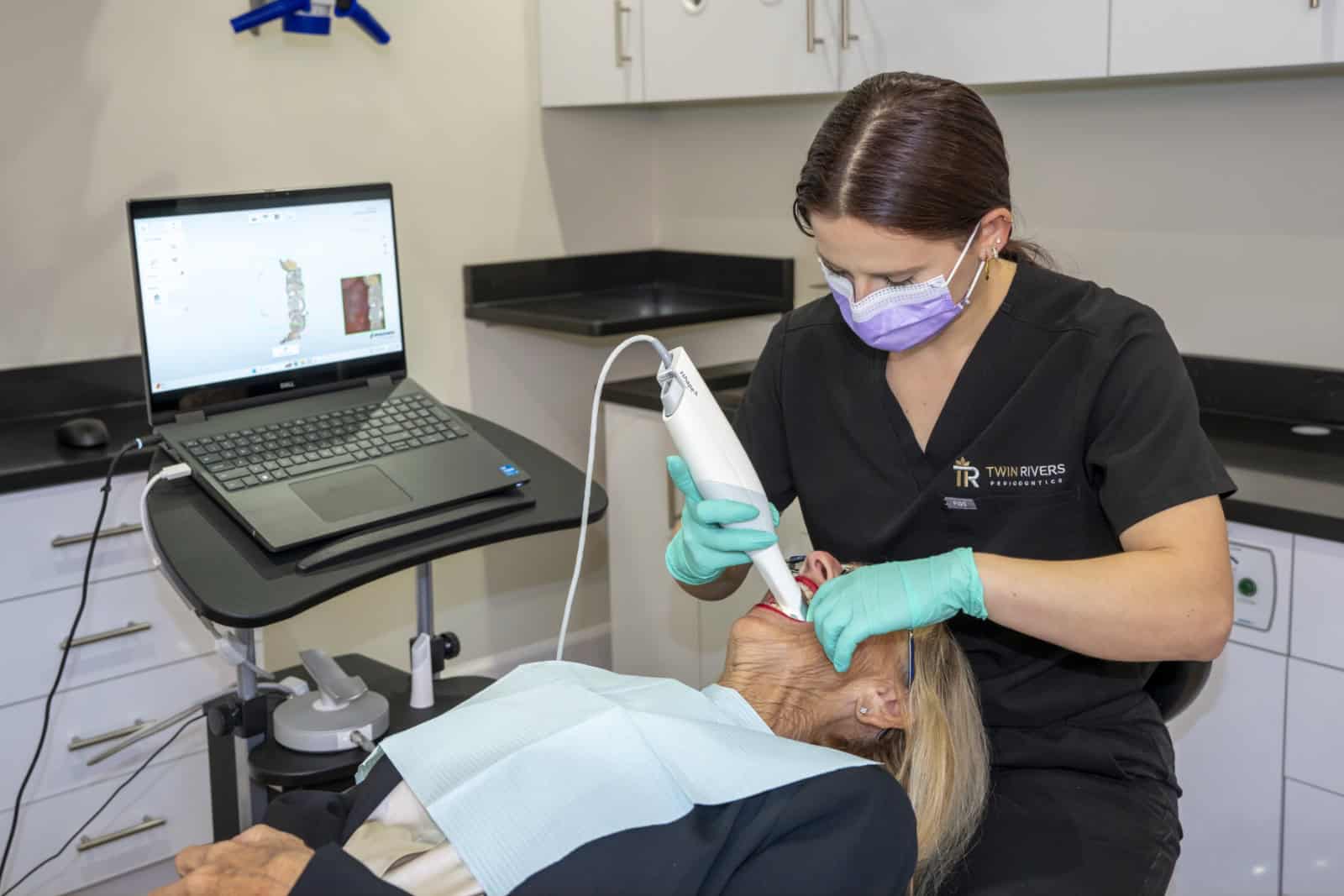 A dental assistant scans a patient's teeth