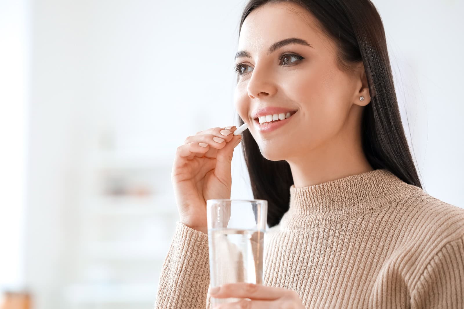 Beautiful young woman taking pills at home