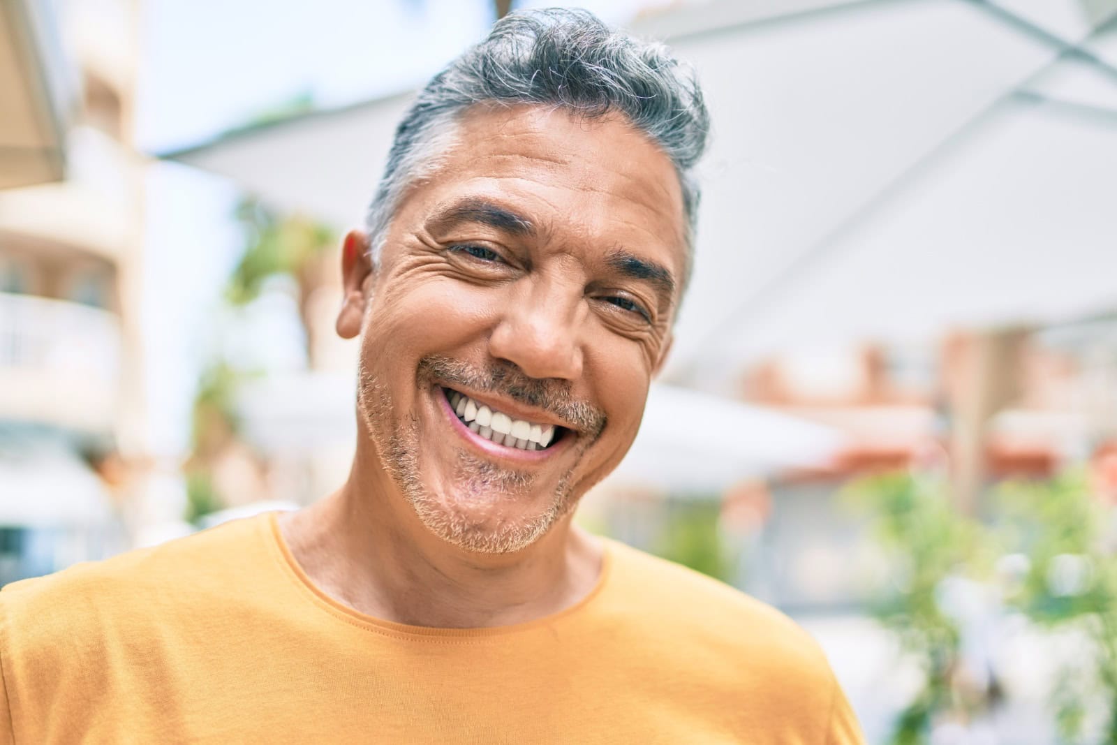 Middle age grey-haired man smiling happy walking at street of city.