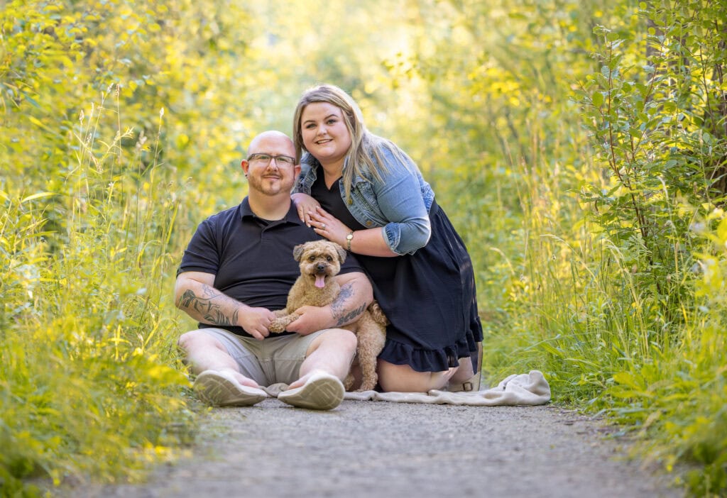 a couple photographed with their dog with beautiful light behind them at Dufferin island in Niagara Falls