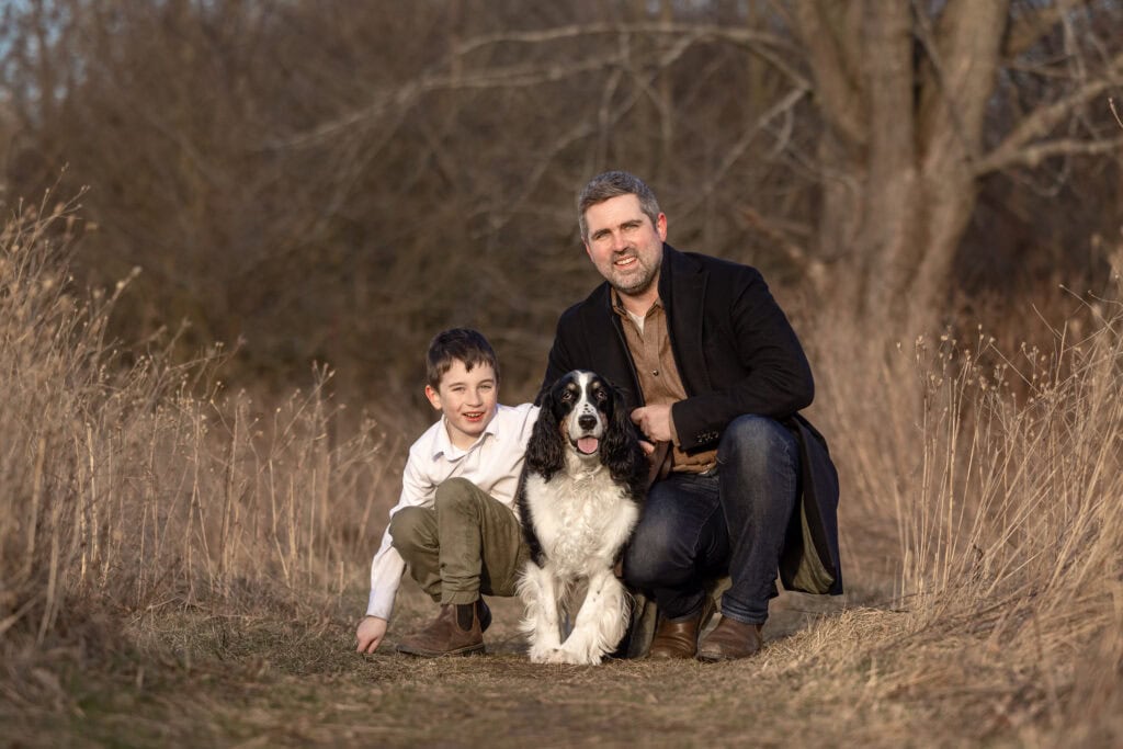 a man and a boy with a dog sitting on a path at Niagara Shores Park in Niagara on the Lake