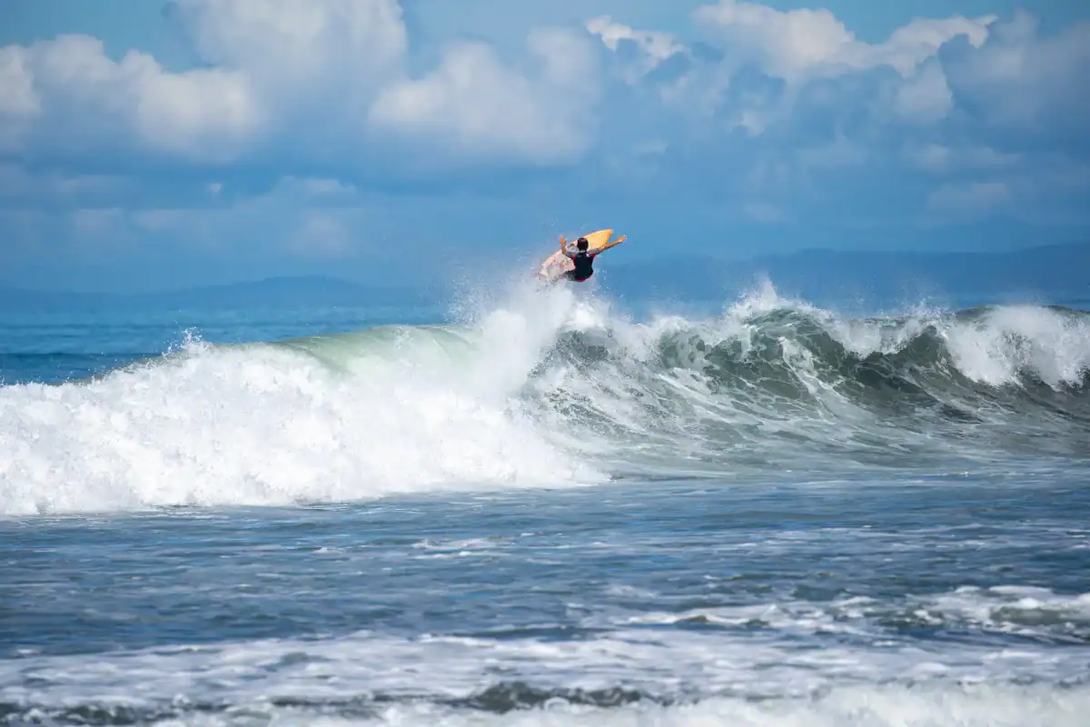 Surfista en una ola en el océano bajo un cielo nublado.