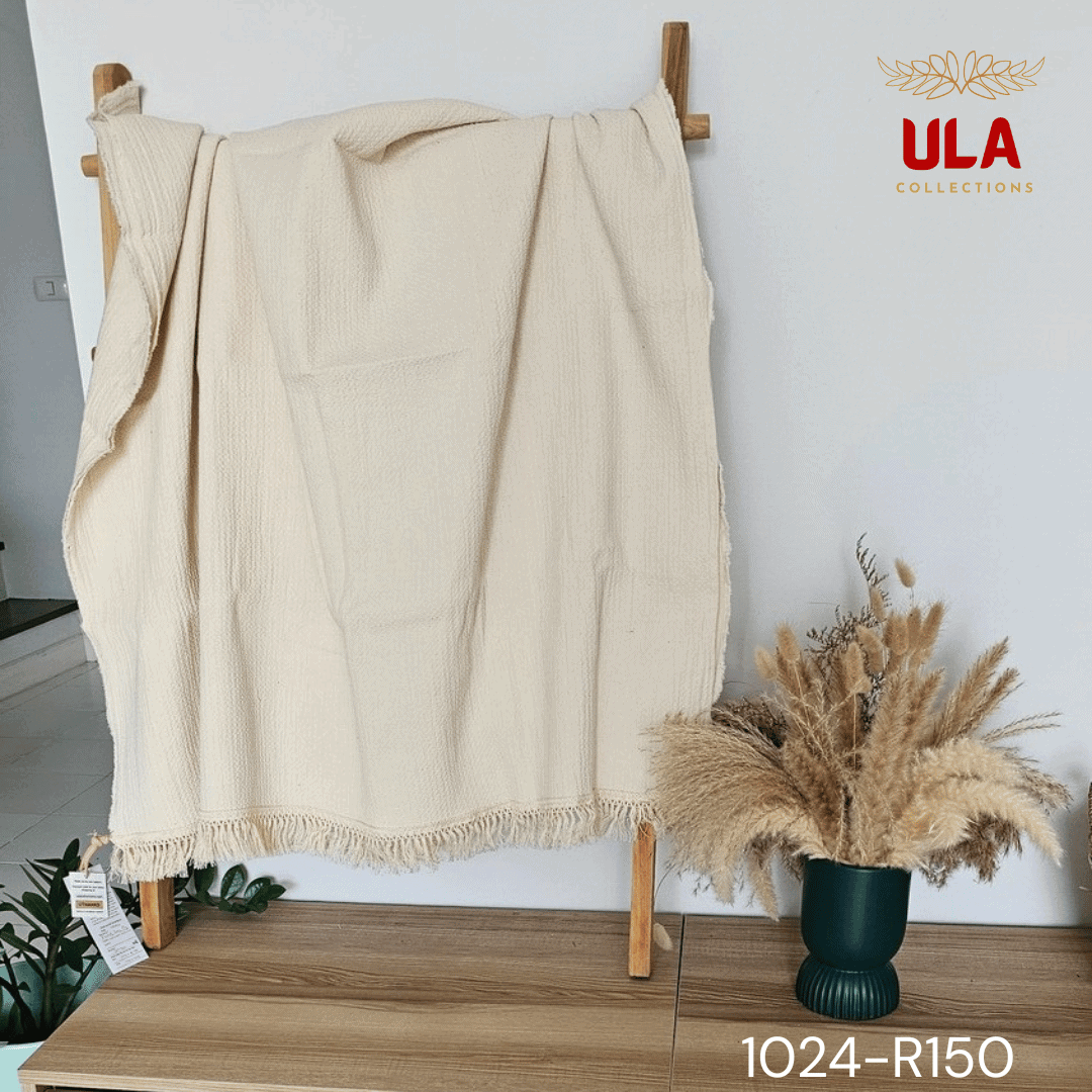 A view of a thick, chunky woven throw blanket in a natural cream or off-white color. The blanket features highly textured details, including vertical wavy ruched ruffles on the left and a wide natural-colored fringe along the bottom. The reverse side shows a simple, thick weave, highlighting its minimalist, bohemian, or modern farmhouse texture for home decor.