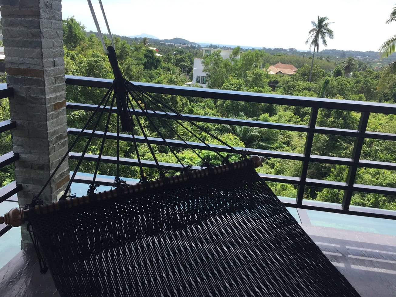 Close-up luxury black rope hammock on a resort balcony with a tropical jungle and mountain view.