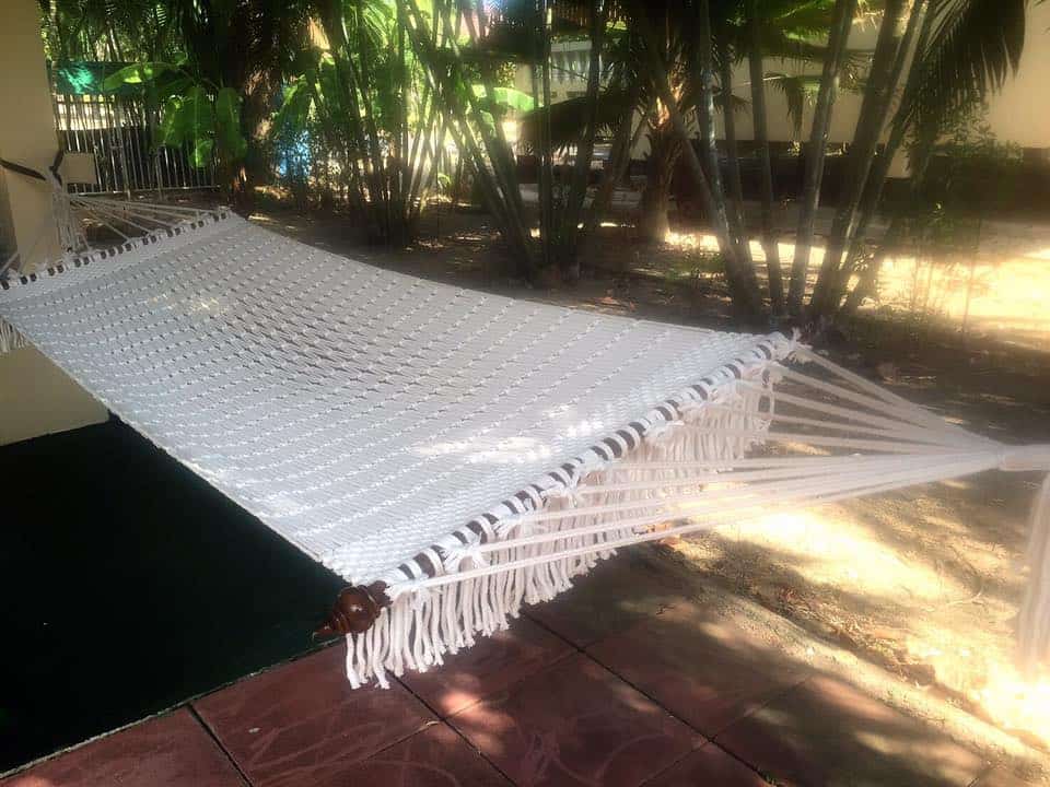 Outdoor white rope hammock for patio and garden comfort.