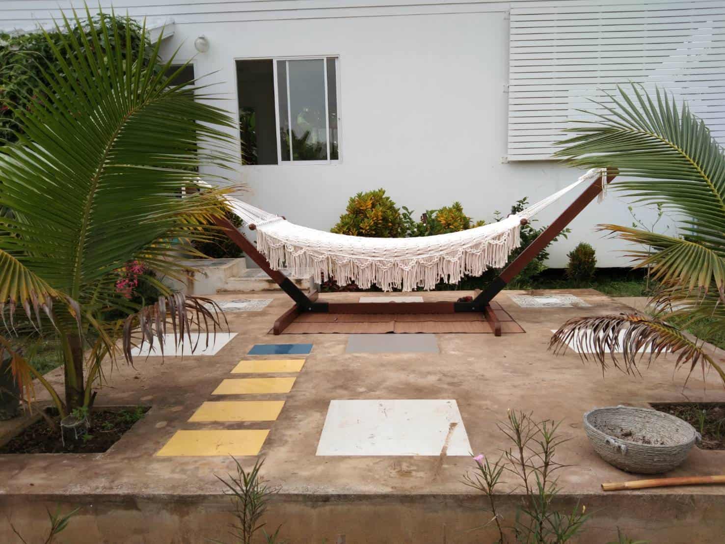 Outdoor beige fringe rope hammock and wooden stand for patio relaxation.